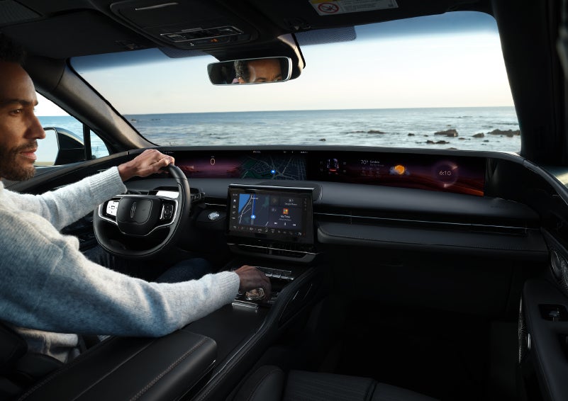 A driver of a parked 2024 Lincoln Nautilus® SUV takes a relaxing moment at a seaside overlook while inside his Nautilus. | White's Canyon Motors - Lincoln in Spearfish SD